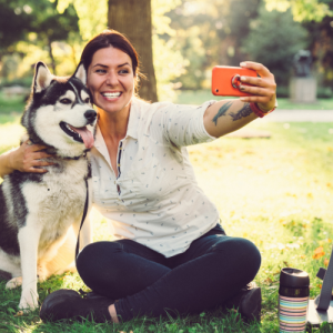 Woman sits taking all american pet photo day shot with husky
